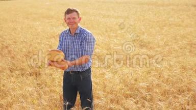 <strong>老农</strong>夫贝克在成熟的麦田里拿着一个金色的面包和面包。慢生活视频。收获时间。古老的